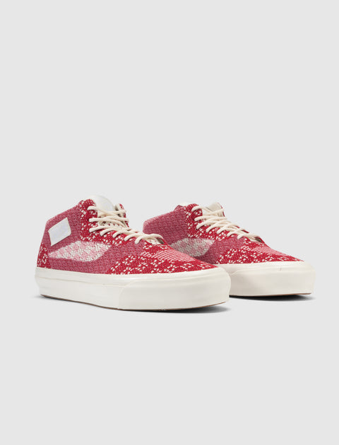 Red and white knit mid-top sneakers with cream soles and white laces on a plain background