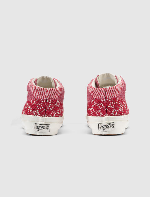 Back view of red and white knit high-top sneakers with white soles on a plain background