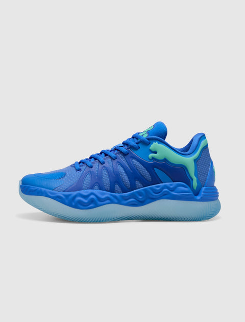 Blue athletic sneaker with wavy sole, mesh upper, and green accents on a white background.