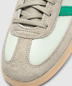 Close-up of mint green and beige suede sneaker toe with gum sole and green side stripe.