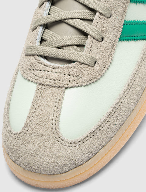 Close-up of mint green and beige suede sneaker toe with gum sole and green side stripe.