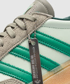 Close-up of mint green sneaker with suede trim, green stripes, and metal tag reading 'DO NOT DUPLICATE'.