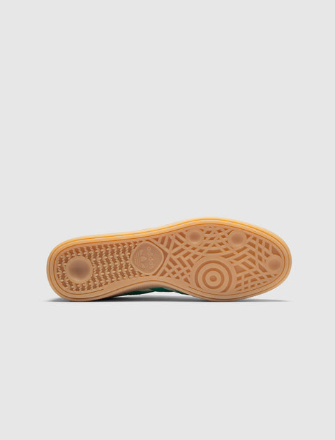 Gum sole of sneaker with circular tread pattern and adidas logo on white background