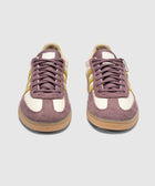 Purple and cream suede low-top sneakers with yellow side stripes on a gum sole, front view