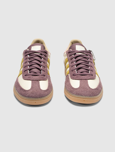 Purple and cream suede low-top sneakers with yellow side stripes on a gum sole, front view