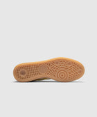 Yellow gum sole of a sneaker with textured tread pattern on white background