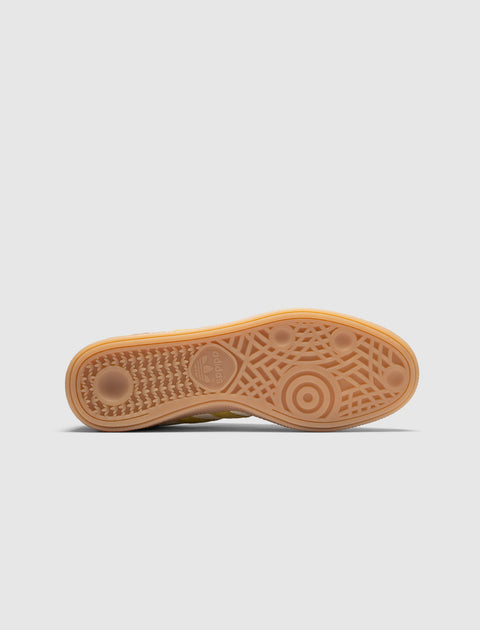 Yellow gum sole of a sneaker with textured tread pattern on white background
