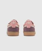 Back view of pink and purple Adidas suede sneakers with gum soles on white background