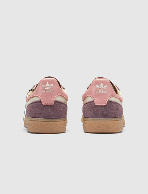 Back view of pink and purple Adidas suede sneakers with gum soles on white background