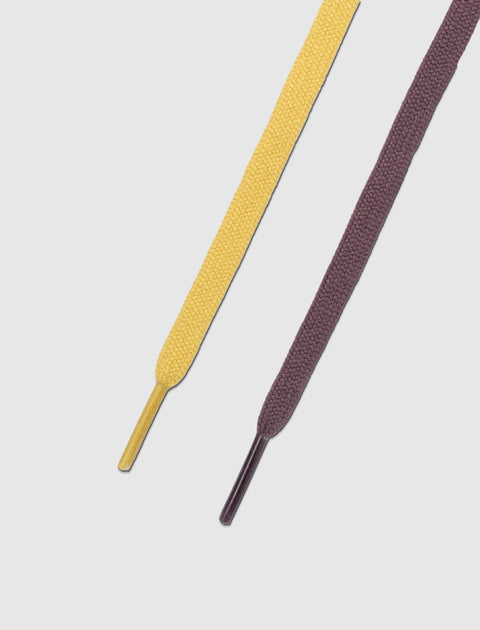 Closeup of yellow and purple flat sneaker laces on a white background