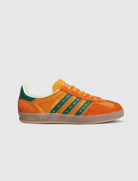 Orange and green low-top sneaker with suede details and gum sole on a light background
