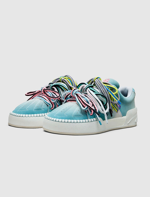Blue low-top sneakers with chunky multicolor laces on a white sole, streetwear style.