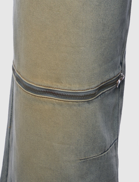 Close-up of stone-washed denim pants with a horizontal zipper detail on the thigh.