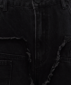 Close-up of black denim jeans with distressed, frayed seam detailing