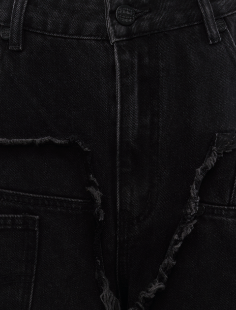 Close-up of black denim jeans with distressed, frayed seam detailing