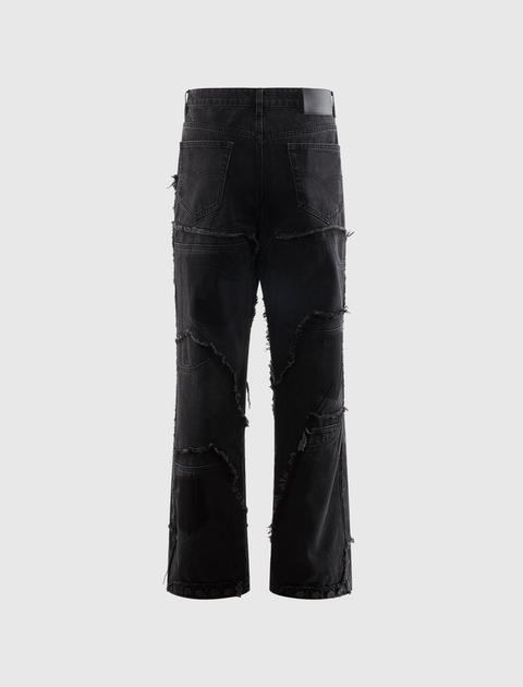 Men's black distressed streetwear jeans with frayed patchwork on a plain background