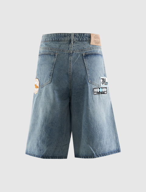 Back view of men's denim shorts with patches and large back pockets on neutral background