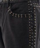 Closeup of black denim jeans with metallic stud detailing along pocket and seam