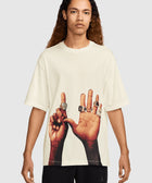 Man wearing cream streetwear t-shirt with graphic of hands displaying rings on the front