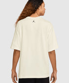 Man wearing an oversized cream t-shirt with small black logo on upper back, streetwear style