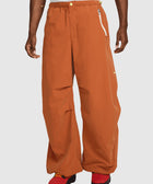 Man wearing loose orange streetwear pants with zip pockets and red sneakers