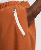 Close-up of orange men's streetwear shorts with white zippered pocket and drawstring waist
