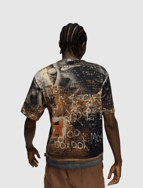 Back view of man wearing Air Jordan graphic t-shirt with graffiti brick wall print