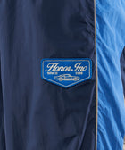 Blue nylon streetwear pants with Honor Inc patch and car graphic detail