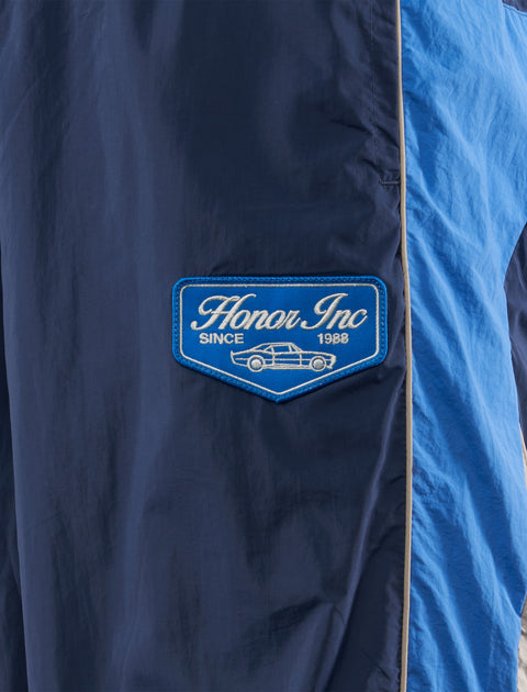 Blue nylon streetwear pants with Honor Inc patch and car graphic detail