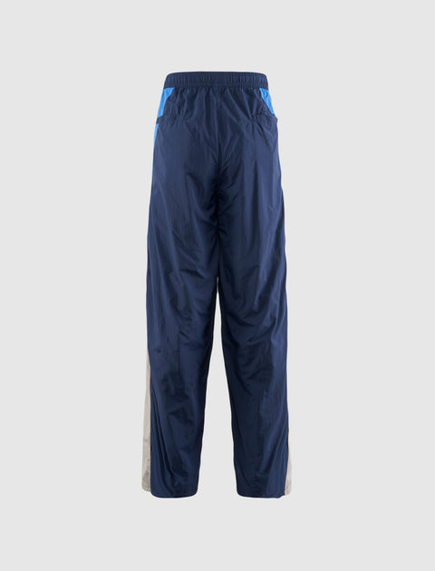 Men's blue nylon track pants with elastic waistband and side panels, rear view