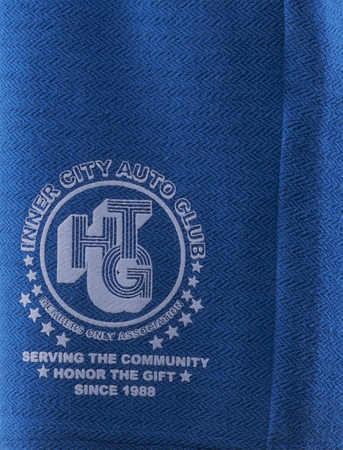 Close-up of blue fabric with Inner City Auto Club graphic and Honor The Gift text.