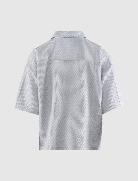 Back view of a light grey textured short sleeve men's shirt on a plain background