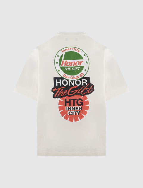 White streetwear t-shirt with bold red, black, and green graphic text and circular logos on back