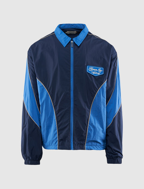Men's blue zip-up streetwear windbreaker jacket with contrast piping and embroidered patch