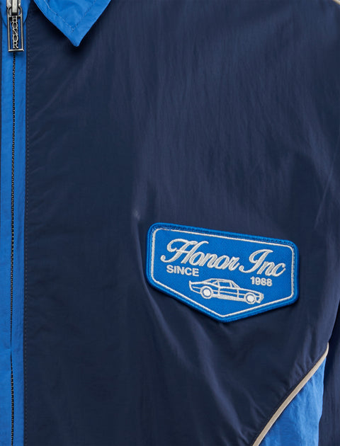 Navy blue windbreaker jacket with Honor Inc patch and car graphic on chest