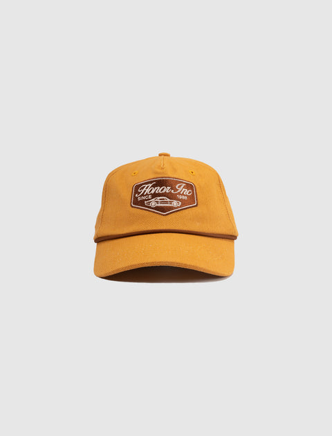 Mustard yellow streetwear baseball cap with embroidered Honor Inc patch on front