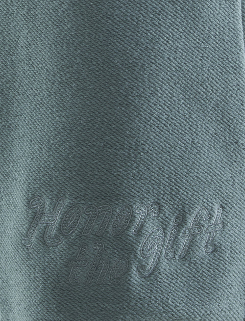 Green textured fabric with 'Honor the Gift' embroidered in matching thread
