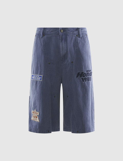 Men's blue denim shorts with embroidered patches and text, streetwear style
