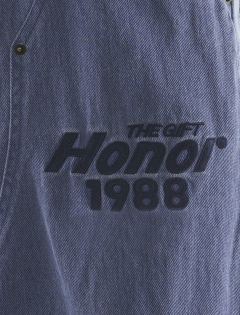 Blue denim fabric with black embroidered text reading 'The Gift Honor 1988'.