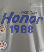 Gray streetwear t-shirt with bold blue 'Honor 1988' text, graphic patches, and slogan detail.