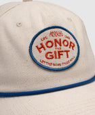 Beige cotton cap with blue piping and red embroidered Honor The Gift patch on front