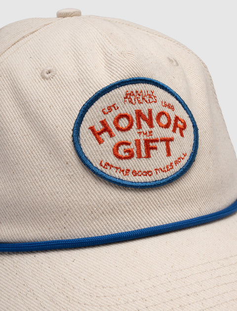 Beige cotton cap with blue piping and red embroidered Honor The Gift patch on front