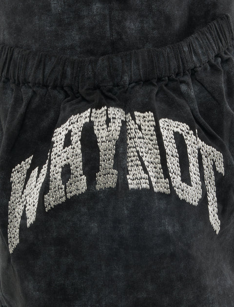 Close-up of black men's streetwear shorts with textured 'WHYNOT' embroidery and elastic waistband