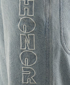 Light blue denim pants with HONOR embroidered in white on the leg