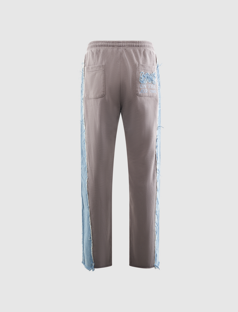 Men's grey streetwear pants with light blue frayed denim side panels and back pockets