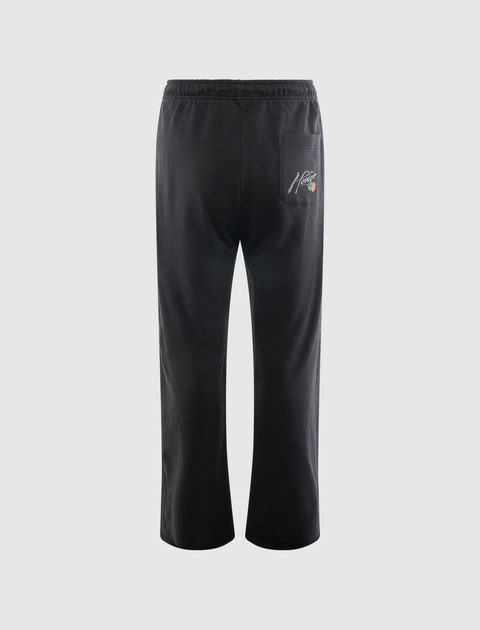 Back view of black men's streetwear pants with graphic text on pocket