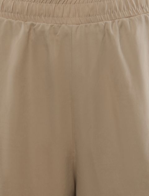 Close-up of beige men's streetwear shorts with elastic waistband and soft fabric