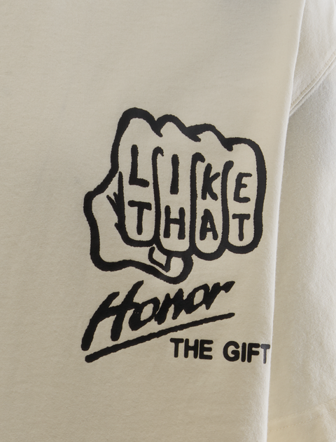 Beige streetwear t-shirt with black graphic fist and text 'LIKE THAT Honor THE GIFT'