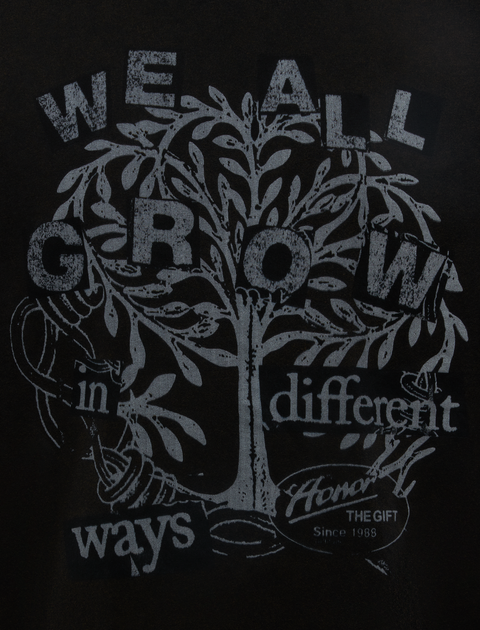 Black streetwear t-shirt graphic with tree and 'We all grow in different ways' text design