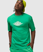 Man wearing green Air Jordan t-shirt and shorts with neon cap, streetwear outfit